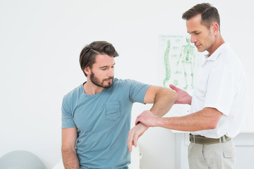 Obraz premium Male physiotherapist examining a young man's arm