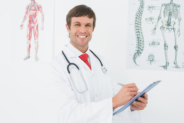 Male doctor holding clipboard in the medical office