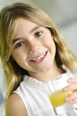 Cute little girl holding glass of fruit juice