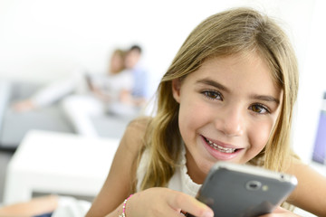 Smiling little girl playing with smartphone