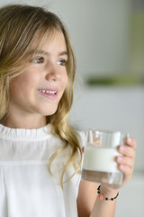 Cute litle girl holding glass of milk