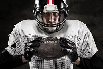 Fotobehang Portrait of american football player holding a ball and looking © guerrieroale