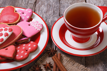 Tea with cinnamon and colorful heart cookies on wooden table