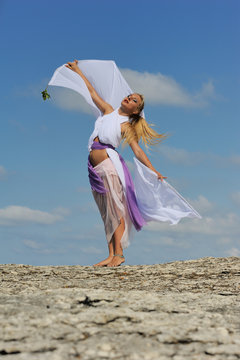 Beautiful blonde girl dancing with clouds