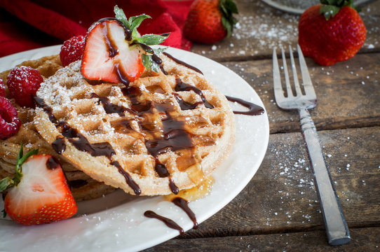 Waffles with strawberries on wooden background