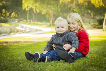 Little Girl with Baby Brother Wearing Coats at the Park.