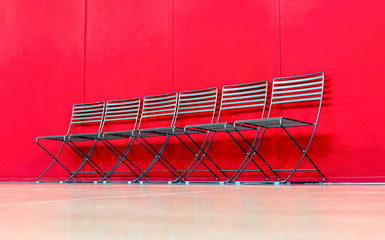 Series of chairs against red wall