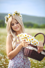 Attractive blonde in chamomile field. Young woman in wreath