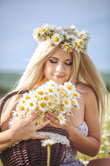 Attractive blonde in chamomile field. Young woman in wreath