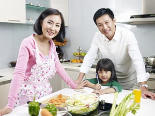 Naklejka premium happy asian family in kitchen