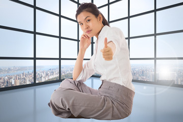 Fototapeta premium Composite image of businesswoman sitting cross legged showing th