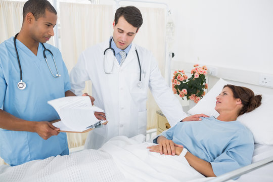 Doctors visiting female patient in hospital