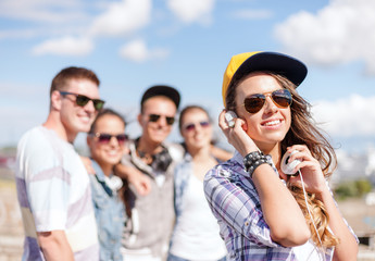 teenage girl with headphones and friends outside