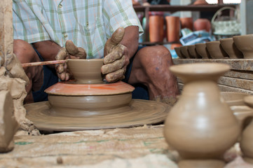 A man shapes pottery as it turns on a wheel
