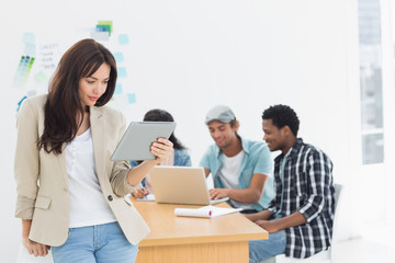 Fototapeta premium Woman using digital tablet with colleagues behind in office
