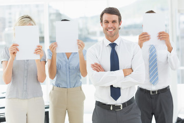 Businessman with colleagues holding blank paper in front of face