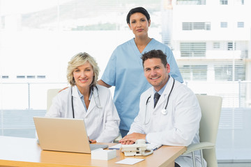 Fototapeta premium Smiling doctors with laptop at medical office