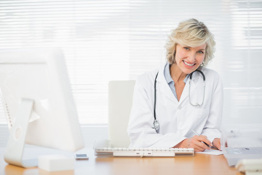 Smiling female doctor with computer at medical office