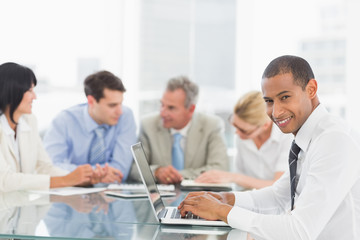 Fototapeta premium Businessman using laptop during a meeting smiling at camera