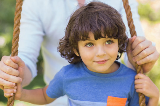 Close-up Of A Father Pushing Cute Boy On Swing