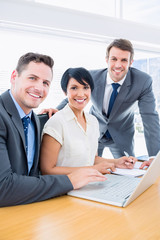 Colleagues using laptop at office desk