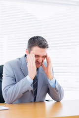 Businessman with severe headache at office desk