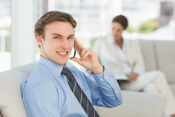 Smiling businessman on the phone sitting on couch