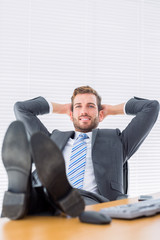 Relaxed businessman sitting with legs on desk