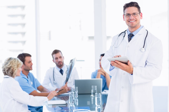 Doctor using digital tablet with colleagues in meeting