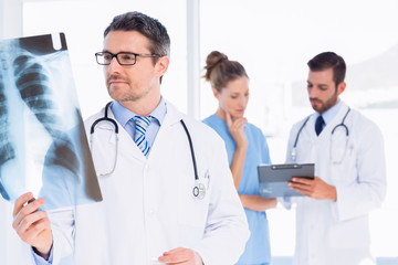 Male doctor examining x-ray with colleagues behind