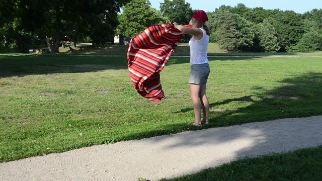 Woman girl with headscarf on head shake rug and flex it in park