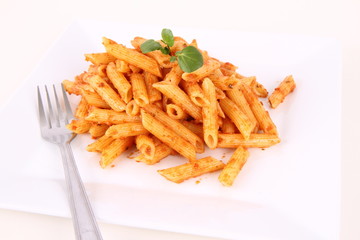 Pasta with pesto rosso being decorated with cress