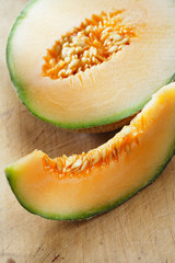Cantaloupe melon slice and one half on wooden table