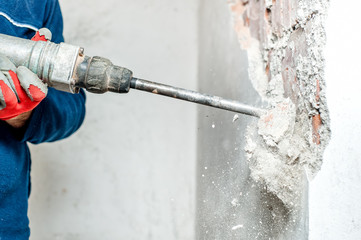 man using a jackhammer to drill into wall. professional worker - obrazy, fototapety, plakaty