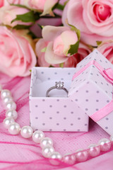 Rose and engagement ring on pink cloth