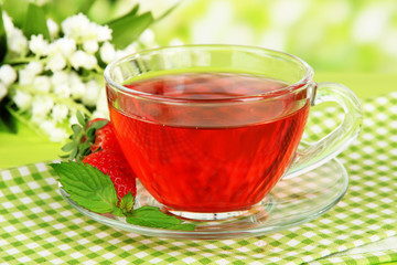Delicious strawberry tea on table on bright background