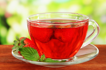 Delicious strawberry tea on table on bright background