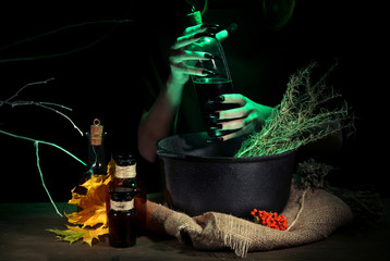 Witch in scary Halloween laboratory on dark color background