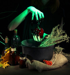 Witch in scary Halloween laboratory on dark color background