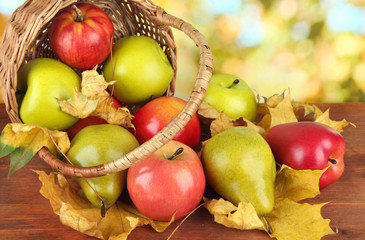 Beautiful ripe apples and pears with yellow leaves in basket