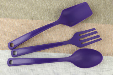 Plastic kitchen utensils on fabric background