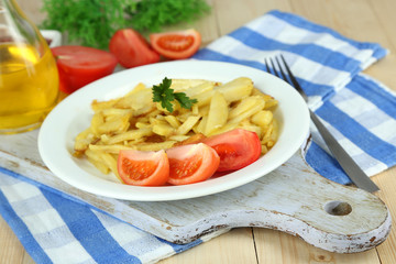 Ruddy fried potatoes on plate on wooden table close-up
