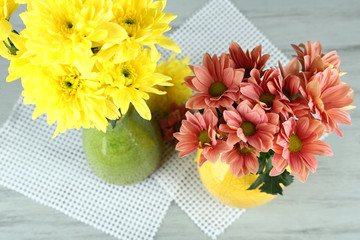 Beautiful flowers  in vases, on wooden table background
