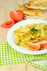 Fried potatoes on plate on wooden table close-up