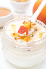 yoghurt with honey, peaches, nuts in a spoon