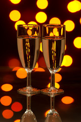 Glasses with champagne against colorful lights
