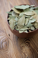 Bowl with dried bay leaves on a wooden table