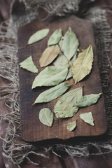 Rustic wooden cutting board with dried bay leaves, vertical shot
