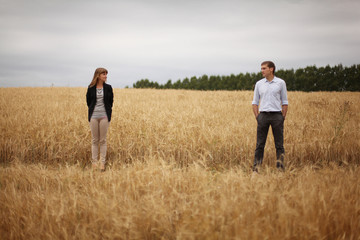Naklejka na ściany i meble young man and woman walking in a field of wheat