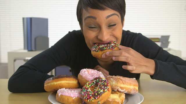 Black business woman eating a pile of donuts